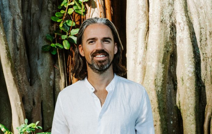 Investor in white linen shirt by a tree—regenerative approach to venture and conscious capital.